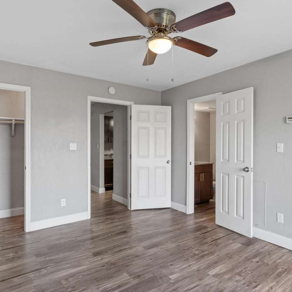 A room with a ceiling fan and white doors.